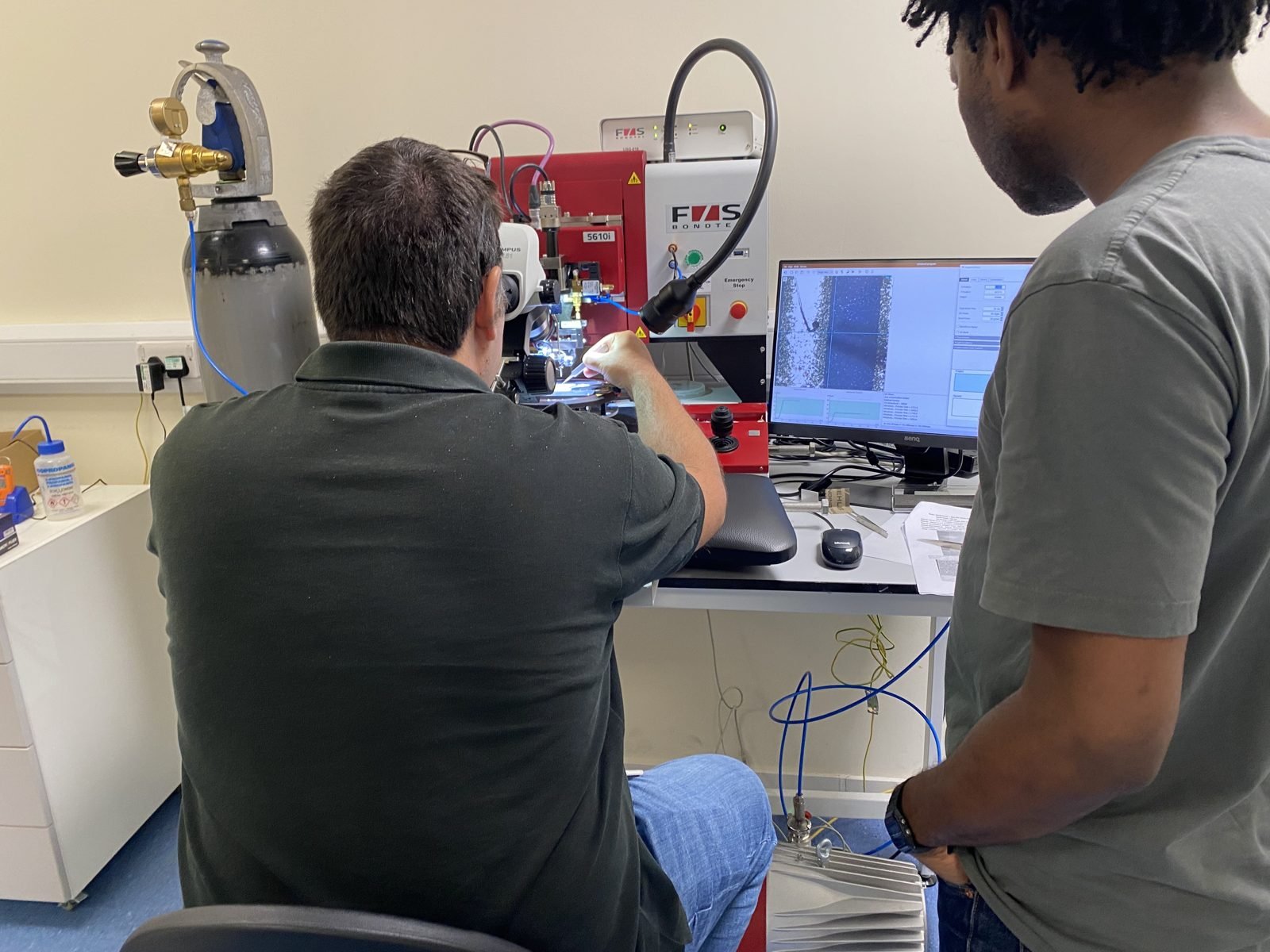 Two group members wire bonding a device on the F&S Bondtec 5610i ball-wedge bonder